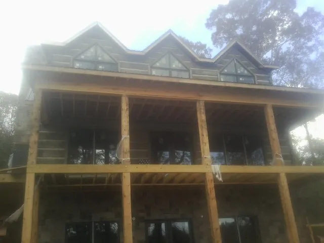 Dormers and porch framing on a large log home under construction — Roof Coating work by our crew in Colmar