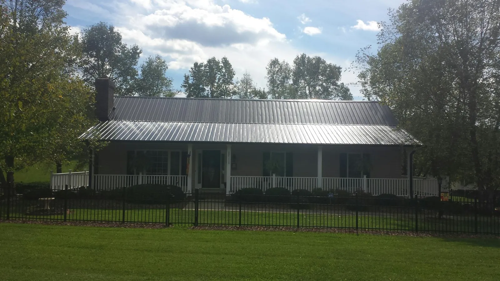 Gray metal roof on a brick ranch with a full width front porch — Gutter Guard Installation work by our crew in Colmar