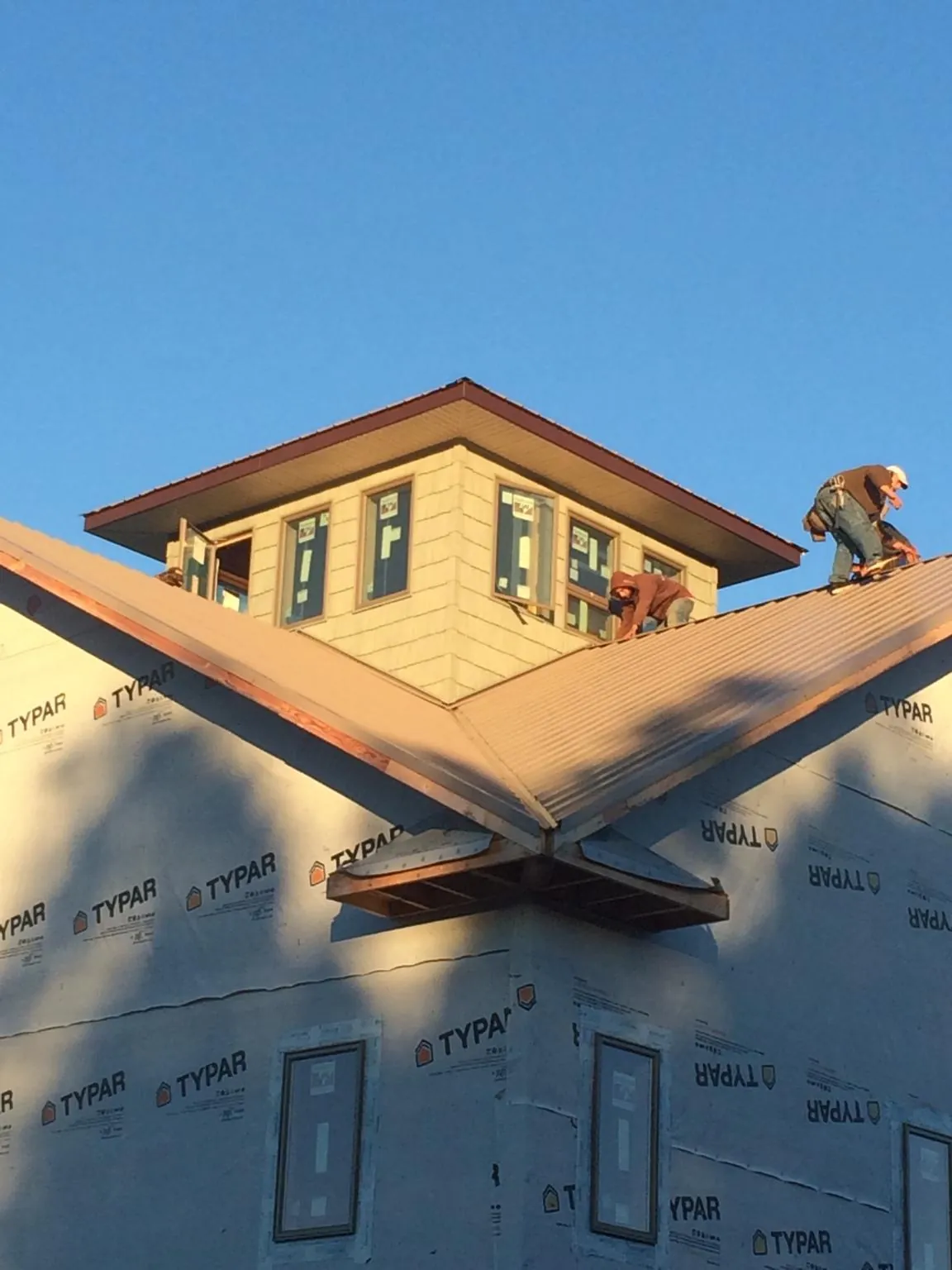 Roofers working around a rooftop cupola on a new metal roof at sunset — Roof Waterproofing in Colmar by Roofing Brothers